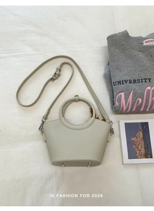 Detail der cremeweißen Beuteltasche mit Lederstruktur und rundem Tragegriff
