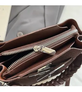 Detail of silver metal zipper and woven leather handle on dark brown bucket bag