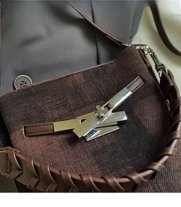 Detail of the silver metallic buckle and woven texture on a brown shoulder bucket bag