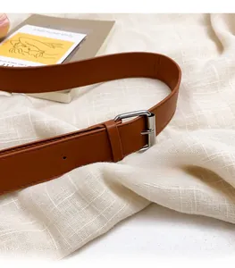 Close-up of adjustable brown leather strap with silver buckle on woven background