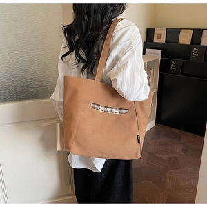 Détail d'un grand cabas en toile camel avec poche à carreaux et logo brodé au studio