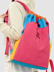 Colorful drawstring patchwork backpack in pink, blue and yellow shown in outdoor setting