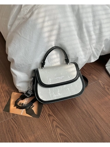 Détail du sac à bandoulière noir et blanc avec texture brossée et fermoir métallique