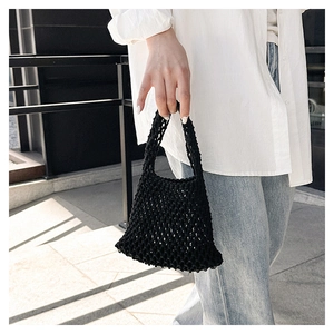 Detail of hand-woven black cotton rope mesh bag showing intricate knot patterns and texture