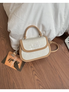 Vue détaillée du sac selle vintage avec texture en soie crème et garniture en cuir
