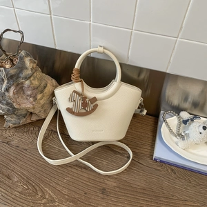 Detailansicht der cremefarbenen Beuteltasche mit Litschi-Maserung und Pferdeanhänger