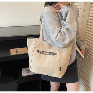 Détail du sac cabas en toile beige avec poche à carreaux marron et bandoulière chic