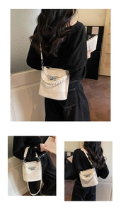 Detail of beige bucket bag with woven handle, metal bow buckle and textured fabric finish