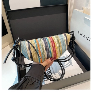 Détail d'un sac demi-lune tissé coloré avec bandoulière nouée sur un coffret cadeau