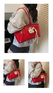Detail of red glossy tote bag with Shante Fashion logo and brown plush bear charm