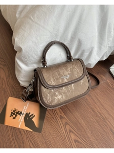 Détail d'un sac demi-lune vintage en cuir marron foncé avec une texture métallique dorée