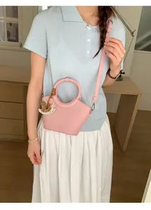 Rosa Eimertasche mit Ringgriff und Pferdeanhänger, von einem Model lässig getragen