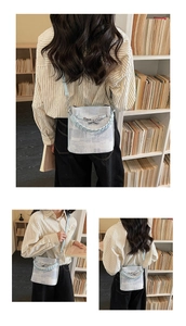 Detail of light blue denim bucket bag with metal bow buckle and woven leather handle