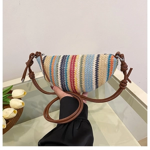 Détail d'un sac bandoulière en paille tressée multicolore avec bandoulière en cuir marron