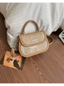 Détail du sac bandoulière marron montrant les bords en cuir grainé et ferrures argent