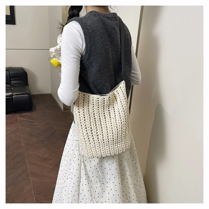 Close-up of the beige hand-woven hollow knit tote bag with elegant black shoulder straps