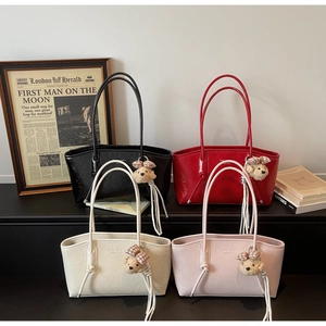 Detail showing four colors of glossy tote bags with bear charms and fringe accents