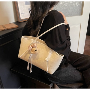 Detail of vintage beige tote bag with pleated leather texture and cute bear charm