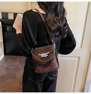 Detail view of brown bucket bag with silver hardware lock and woven top handle