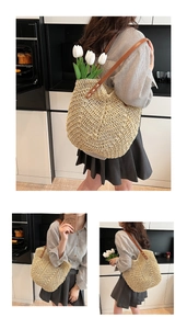 Detailed close-up of handmade woven straw tote with brown faux leather straps and X-stitching