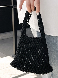 Handmade black hollow woven bucket tote bag with integrated handle for beach travel