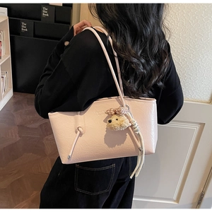 Detail of pink faux leather tote bag showing crinkled texture and dog charm