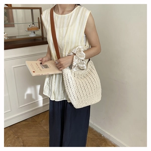 Detail of hand-woven cream tote bag featuring high-quality brown leather shoulder strap