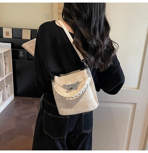Detail view of cream bucket bag with woven handle and metallic rectangular buckle closure