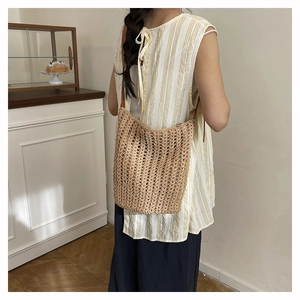 Detail of handwoven straw tote bag with zip closure and slim leather shoulder straps