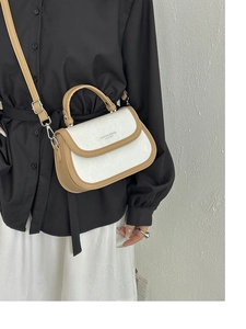 Détail du sac bicolore montrant le rabat blanc avec lettrage et les lanières marron
