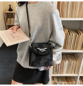 Close-up of vintage textured bucket bag with silver metal lock and braided handle