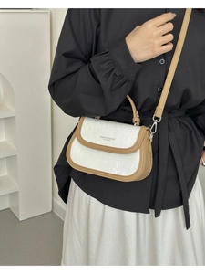 Détail d'un sac à bandoulière blanc texturé avec bordure kaki et logo tendance