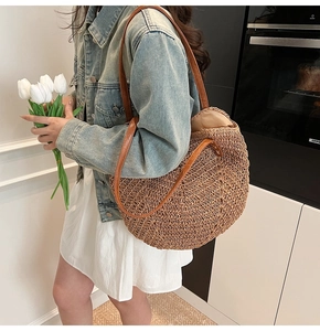 Detail shot of woven straw tote bag with brown faux leather straps for summer beach style