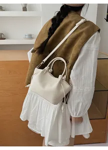 Model wearing a minimalist cream leather bucket bag with drawstring knot details