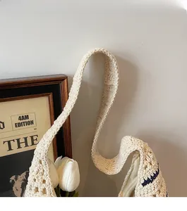 Detail of wide thick shoulder strap on cream handmade crochet straw hobo bag