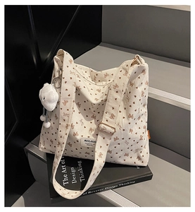 Detailed close-up of corduroy tote bag with brown bow patterns and cloud plush charm