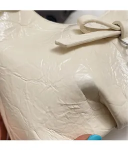 Détail de la texture plissée du sac blanc crème avec un élégant nœud en cuir décoratif