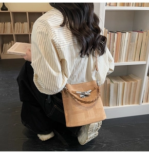 Detail of light brown bucket bag with woven handle and grid texture in a bookstore