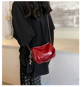 Detailed side view of a glossy red crossbody bag with silver chain and cute dog charm