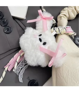 Détail d'un pendentif en peluche blanc avec nœud rose et dentelle sur un sac à main