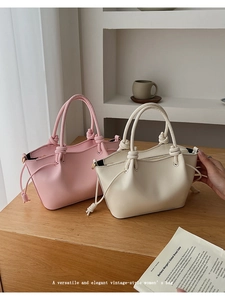 Detail showing elegant knotted handles and drawstrings of pink and beige bucket bags
