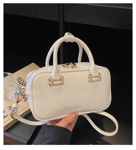 Close-up of white bowling bag featuring embossed logo detail and light gold hardware
