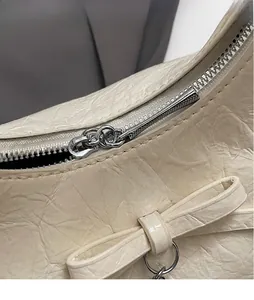 Détail du sac en cuir plissé blanc crème avec fermeture éclair argentée et nœud
