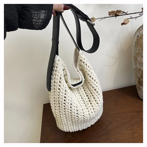 Close-up of cream woven tote bag texture with premium black leather shoulder strap detail