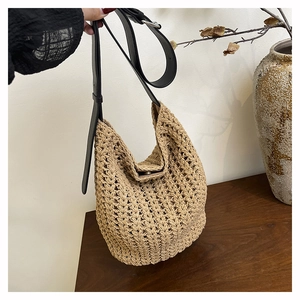 Detail of beige crochet tote bag with adjustable black leather strap and metal magnetic closure