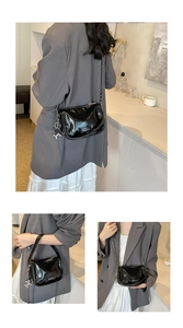 Close-up of glossy black leather crossbody bag with silver chain and Fashion label