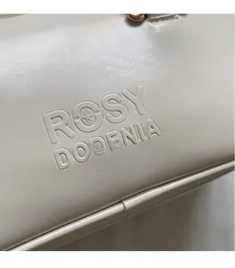 Close-up of embossed ROSY DORENIA logo on high-quality matte faux leather beige handbag