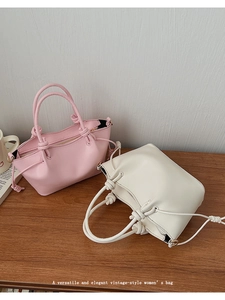 Detail view of pink and beige minimalist handbags with knotted handles and drawstrings