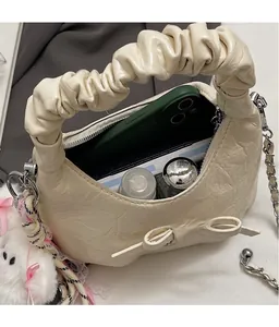 Détails intérieurs d'un sac à bandoulière crème plissé avec chaîne et breloque lapin