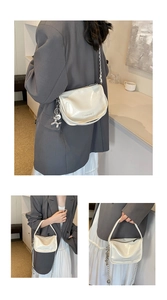 Detailed view of white patent leather handbag featuring a silver balloon dog pendant charm